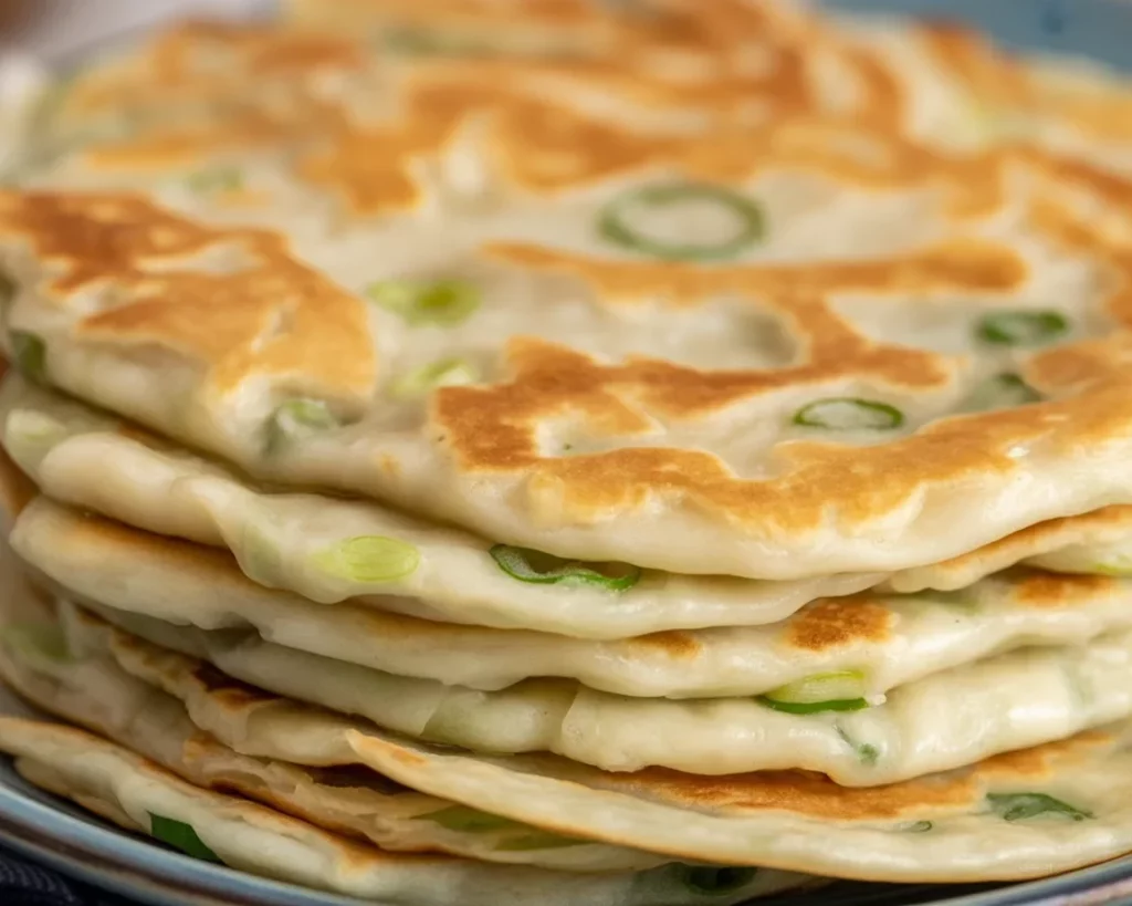 Herzhafte vegane Pfannkuchen mit Spinatfüllung in der Pfanne zubereitet.